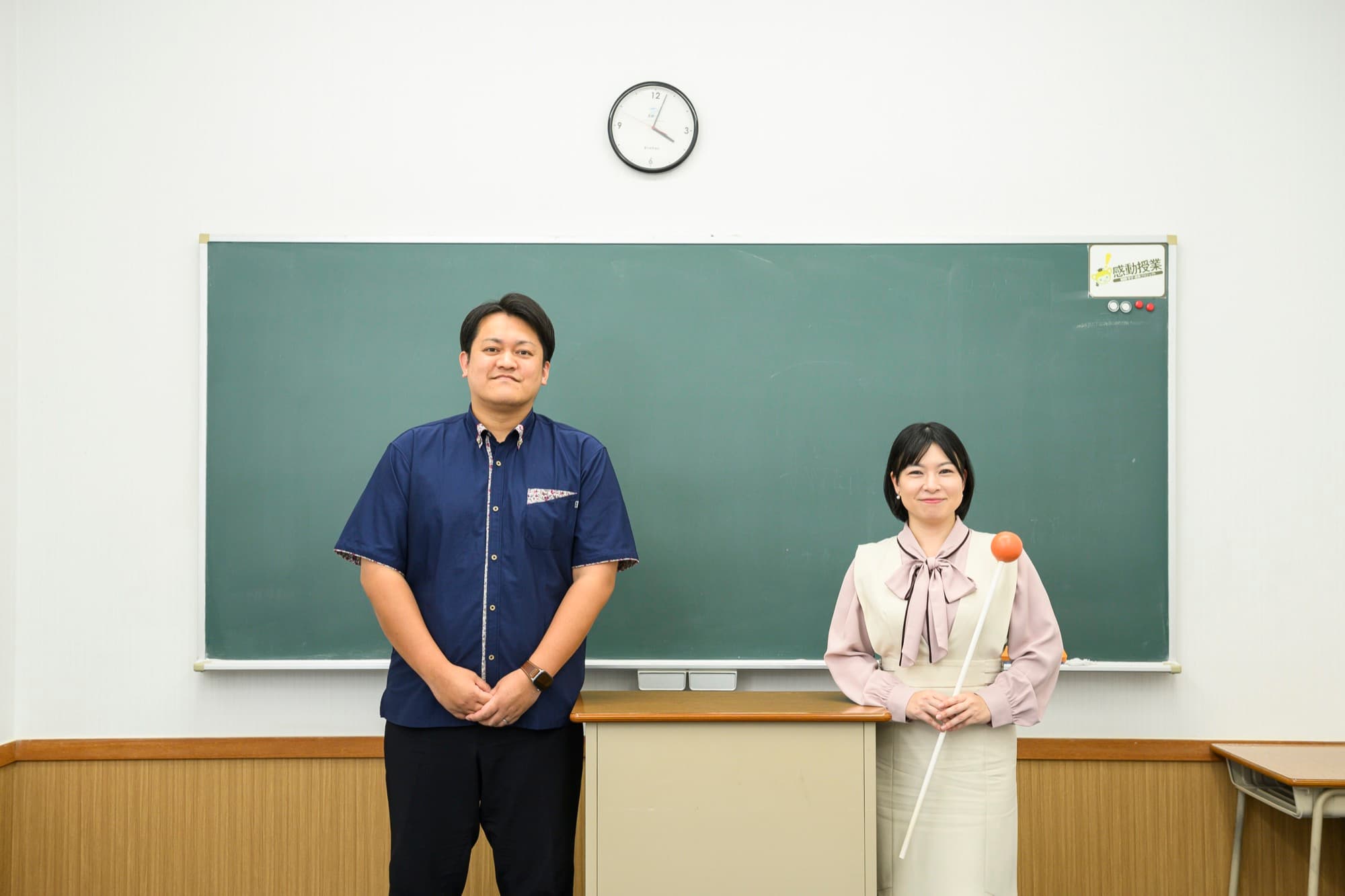 教室の黒板の前に並んで立つ根間幸大さんと池宮城サキさん