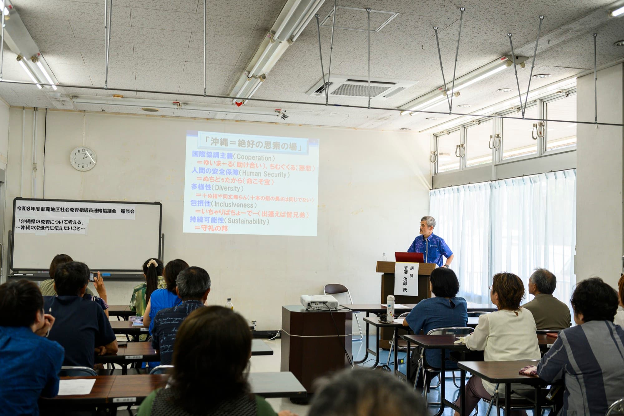 研修会の会場で、スクリーンの前に立って講演する官澤治郎先生