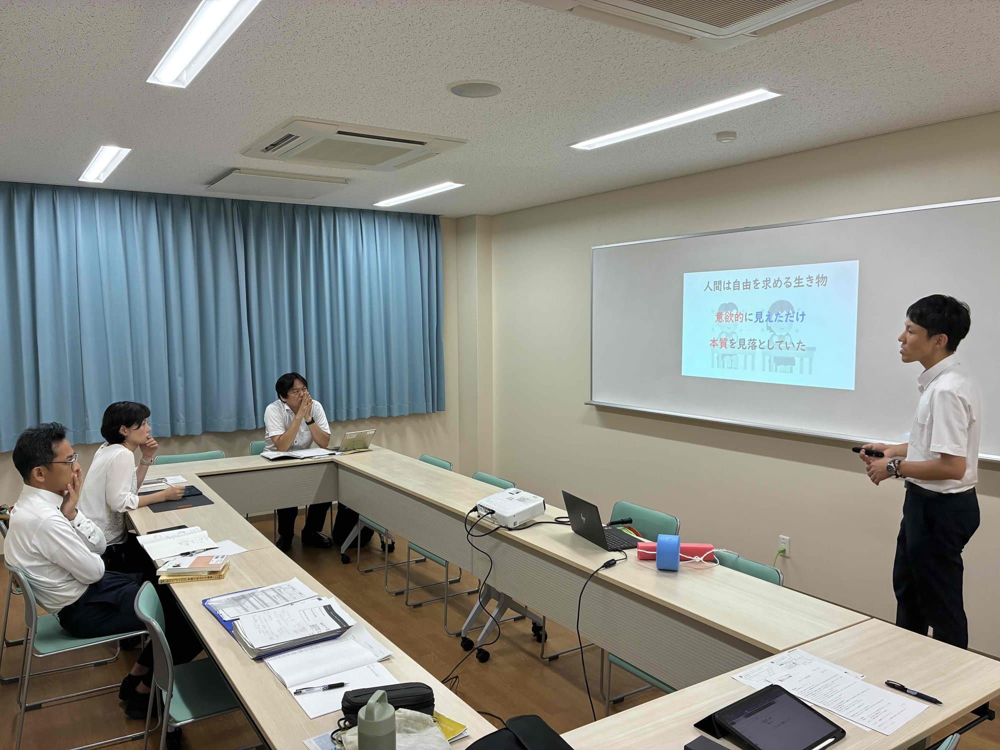 会議室で講師の話を聞く先生たち