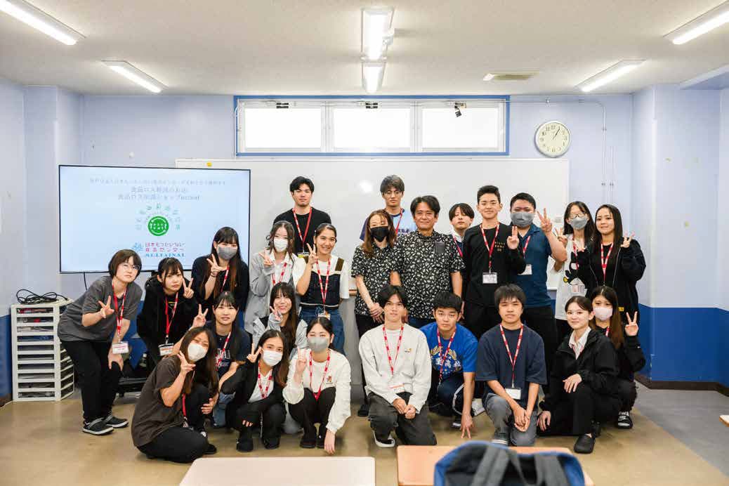 教室のスクリーンの前で並ぶ、那覇日経ビジネス専門学校の学生と玉城淳一郎さん