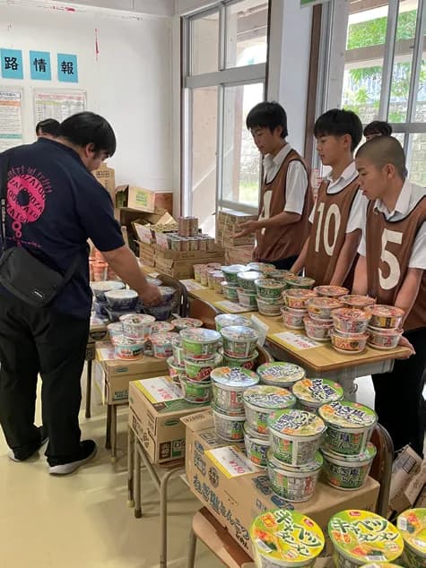 机に並んだ商品の前で、来店者に対応する生徒